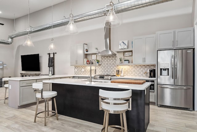 kitchen with stainless steel fridge, a towering ceiling, wall chimney exhaust hood, a breakfast bar, and open shelves