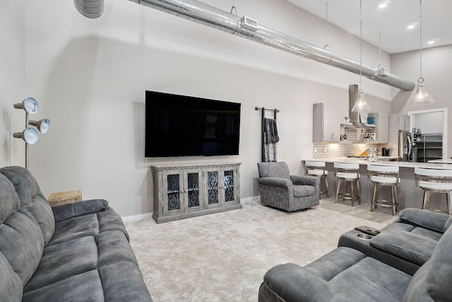 living area with light carpet, a high ceiling, and baseboards