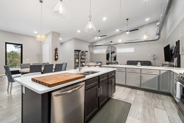 kitchen featuring light countertops, appliances with stainless steel finishes, open floor plan, a sink, and an island with sink