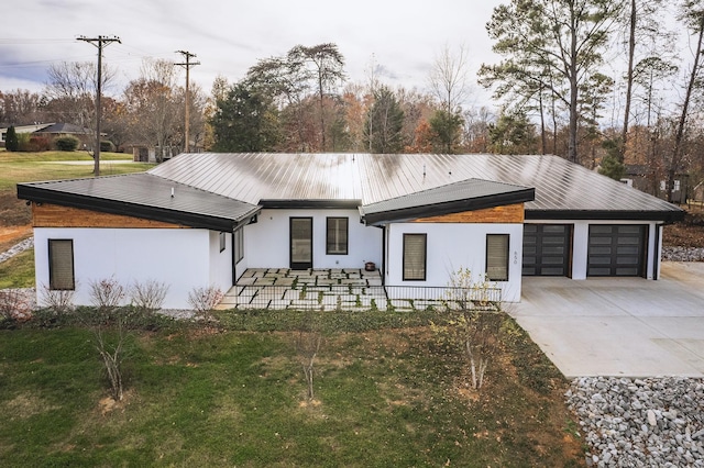 view of front of house with a garage, covered porch, concrete driveway, stucco siding, and a front yard