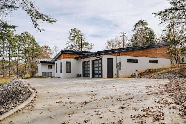 back of property with an attached garage, metal roof, a standing seam roof, and concrete driveway