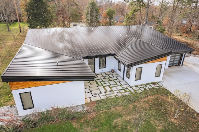 contemporary house featuring a garage, metal roof, concrete driveway, and stucco siding