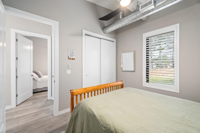 bedroom with visible vents, baseboards, a ceiling fan, light wood-style flooring, and a closet