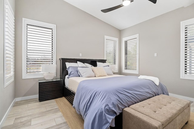 bedroom with vaulted ceiling, light wood-type flooring, a ceiling fan, and baseboards