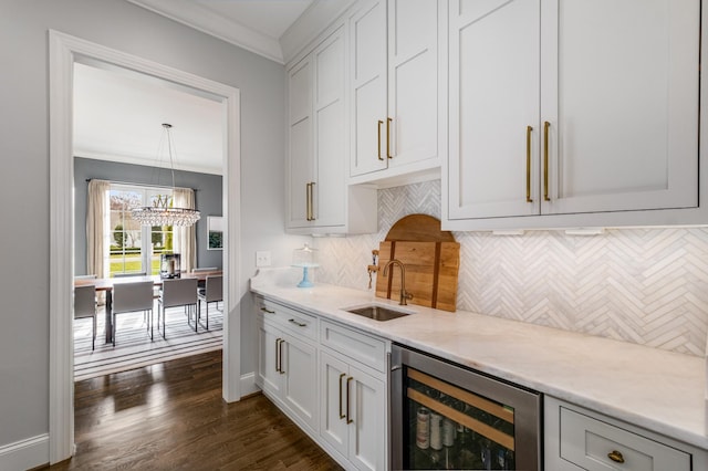 kitchen featuring beverage cooler, dark wood-type flooring, a sink, decorative backsplash, and crown molding