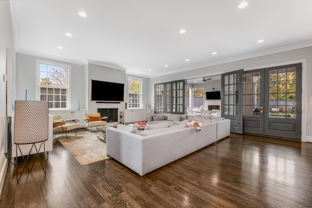 living room with french doors, dark wood-type flooring, a brick fireplace, and a healthy amount of sunlight