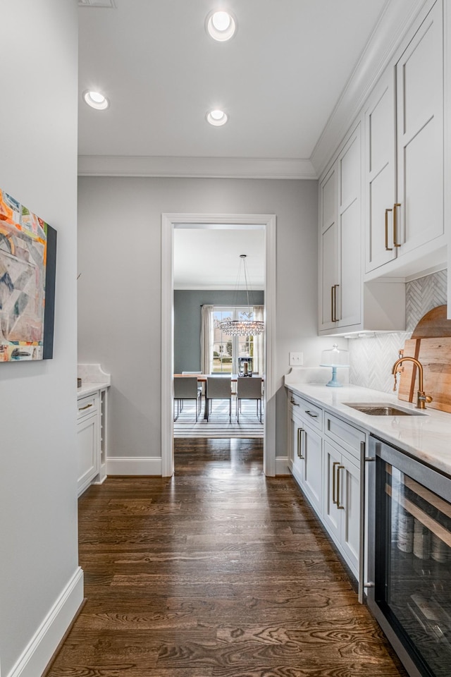 kitchen featuring dark wood-style flooring, decorative backsplash, ornamental molding, a sink, and beverage cooler