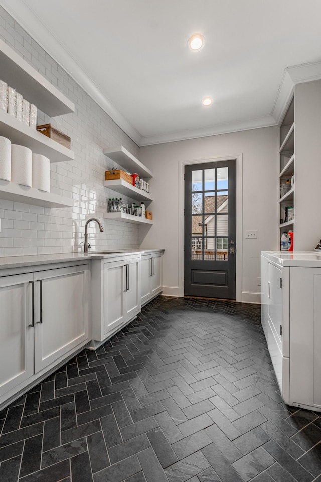 interior space featuring crown molding, recessed lighting, cabinet space, a sink, and independent washer and dryer