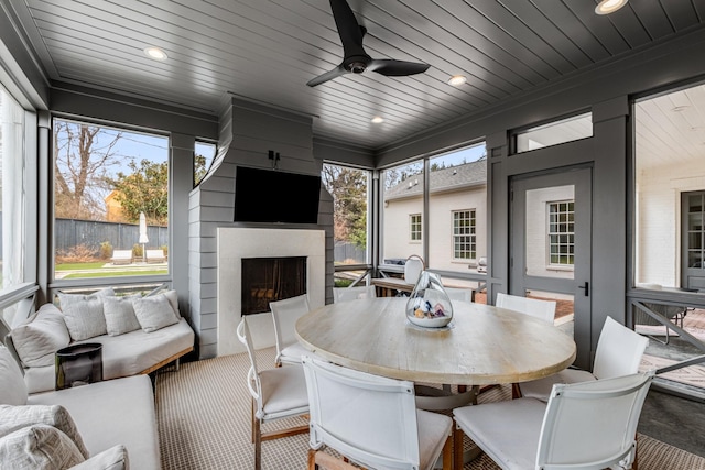 sunroom / solarium featuring a ceiling fan, wooden ceiling, and a fireplace