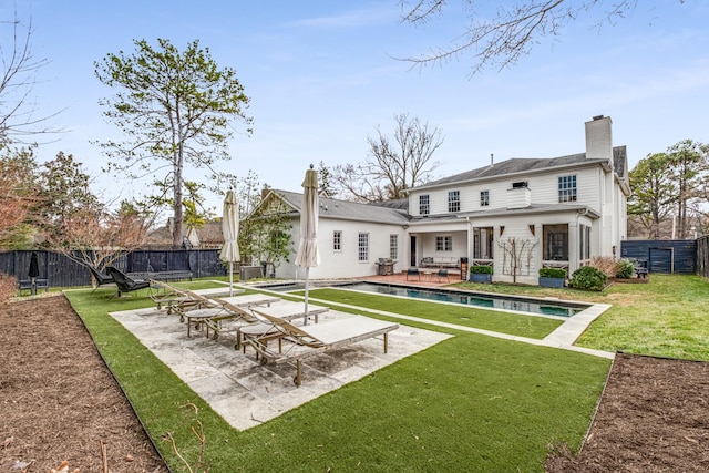 back of house featuring a patio, a fenced backyard, a lawn, a fenced in pool, and a chimney