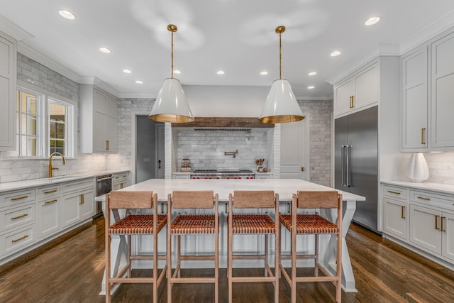 kitchen featuring built in fridge, dark wood-type flooring, a kitchen breakfast bar, and extractor fan