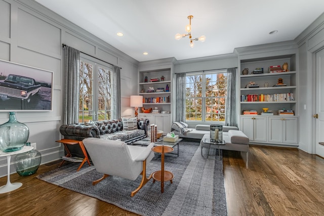 sitting room with a notable chandelier, plenty of natural light, built in shelves, and wood finished floors