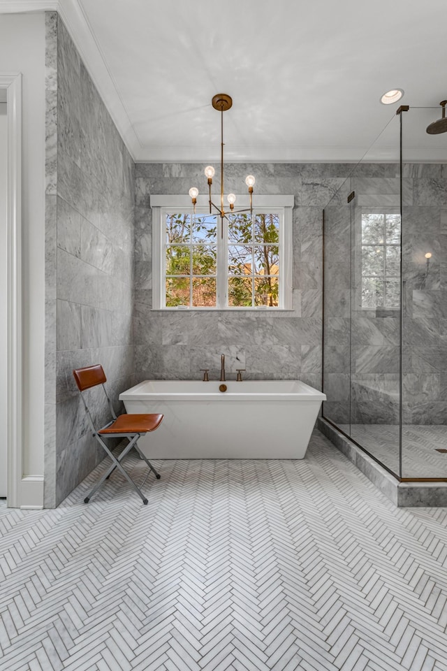 full bathroom featuring a chandelier, tile patterned flooring, tile walls, a freestanding bath, and a marble finish shower