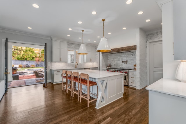 kitchen featuring a center island, white cabinets, decorative backsplash, dark wood-style floors, and stainless steel range