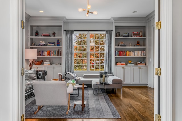 sitting room with built in features, a chandelier, ornamental molding, and wood finished floors