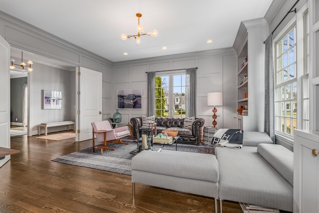 living room featuring ornamental molding, dark wood-style flooring, a decorative wall, a notable chandelier, and recessed lighting