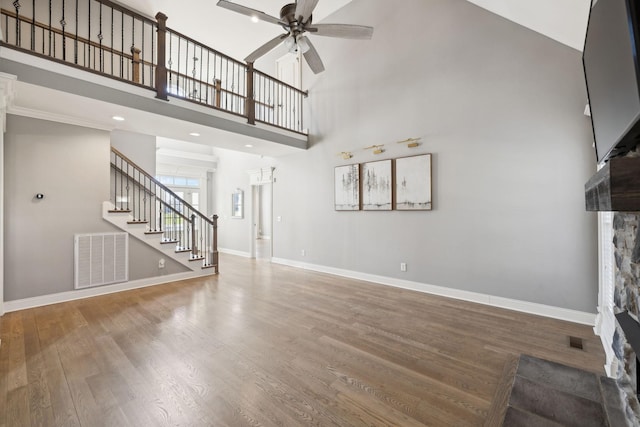 unfurnished living room featuring baseboards, visible vents, ceiling fan, wood finished floors, and stairs