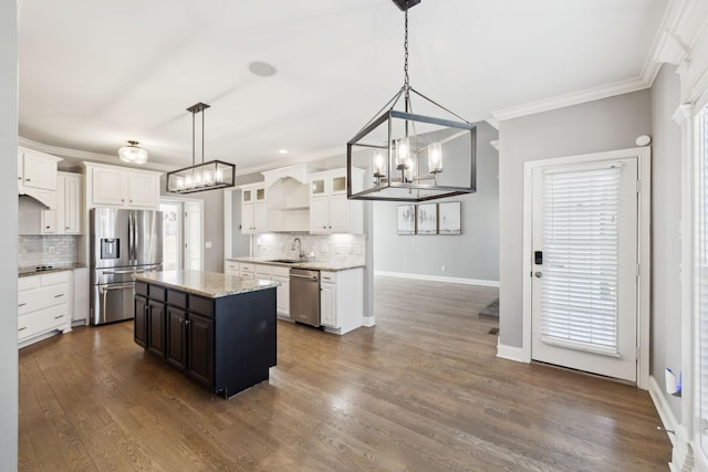 kitchen with a sink, white cabinets, appliances with stainless steel finishes, dark wood-style floors, and crown molding