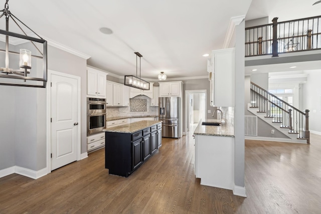 kitchen with stainless steel appliances, a sink, white cabinetry, and a center island