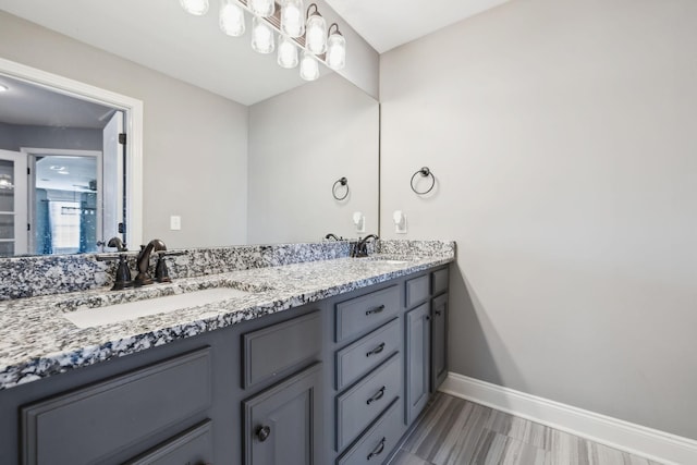 full bath featuring double vanity, a sink, and baseboards