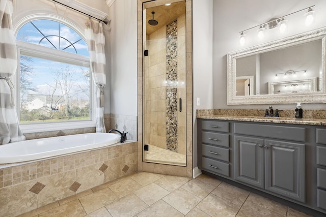 bathroom featuring a stall shower, tile patterned flooring, a garden tub, and vanity