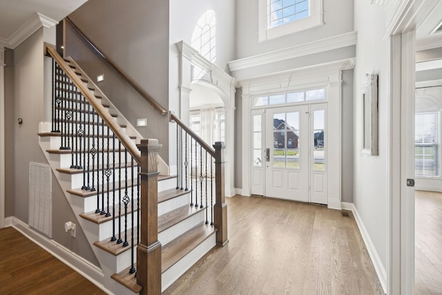 entryway featuring a wealth of natural light, visible vents, decorative columns, and wood finished floors