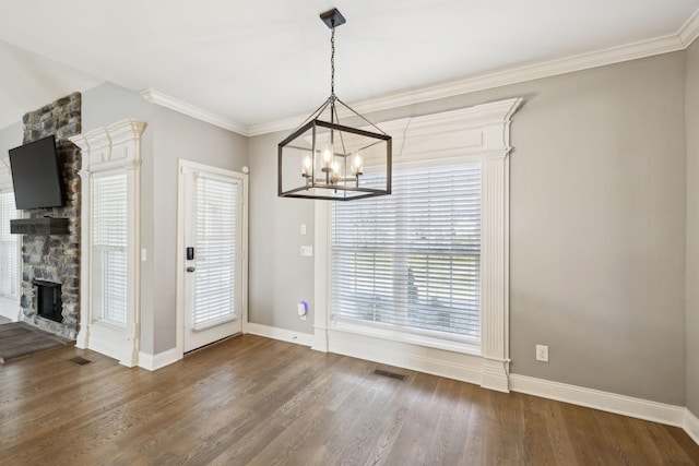 unfurnished dining area with baseboards, visible vents, wood finished floors, crown molding, and a stone fireplace