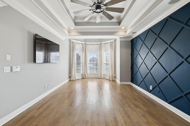 unfurnished room featuring ornamental molding, a tray ceiling, baseboards, and wood finished floors