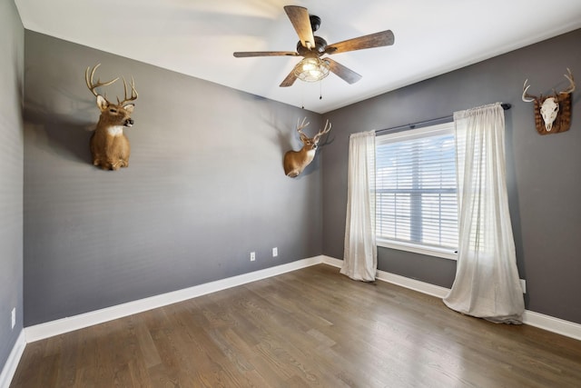 empty room with ceiling fan, baseboards, and wood finished floors