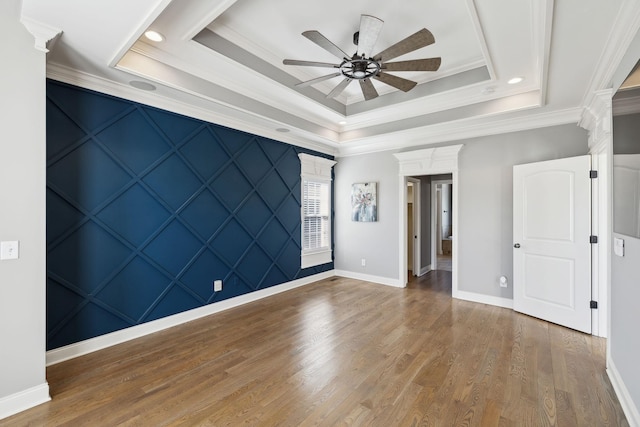 unfurnished room featuring baseboards, crown molding, a tray ceiling, and wood finished floors