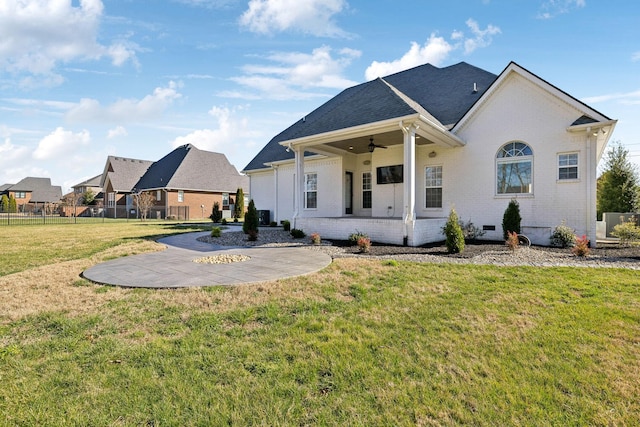 rear view of house featuring ceiling fan, a patio, brick siding, fence, and a yard