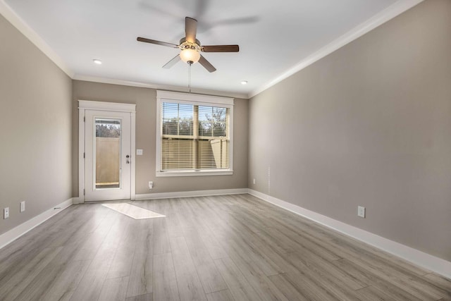 spare room featuring ornamental molding, baseboards, and wood finished floors