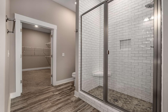 bathroom featuring a shower stall, toilet, and wood finished floors