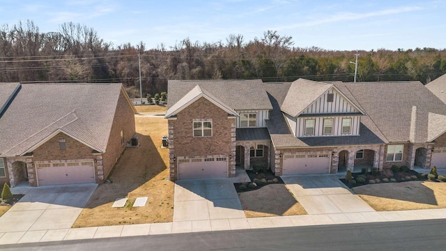 view of front facade featuring a shingled roof, concrete driveway, and brick siding