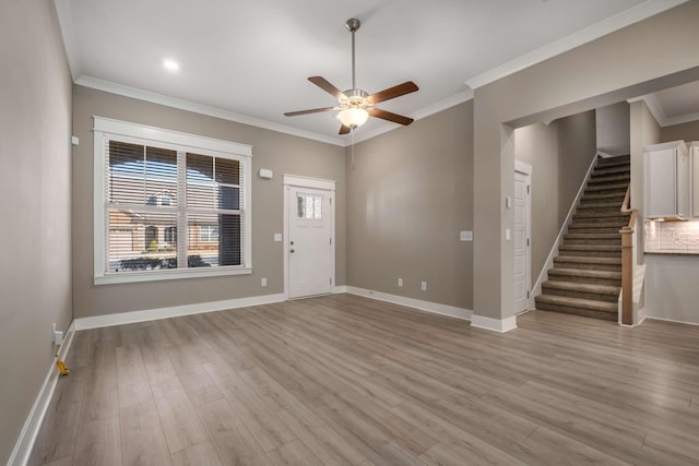 interior space with baseboards, ceiling fan, ornamental molding, stairs, and light wood-style floors