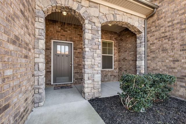 doorway to property featuring covered porch and brick siding