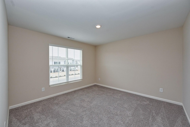 unfurnished room with carpet, visible vents, and baseboards