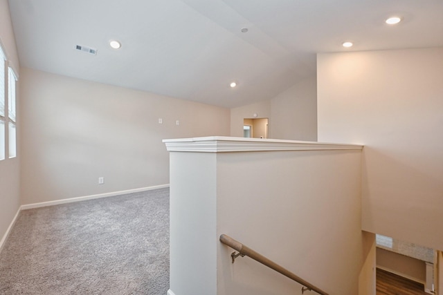 hallway featuring lofted ceiling, visible vents, carpet flooring, an upstairs landing, and baseboards