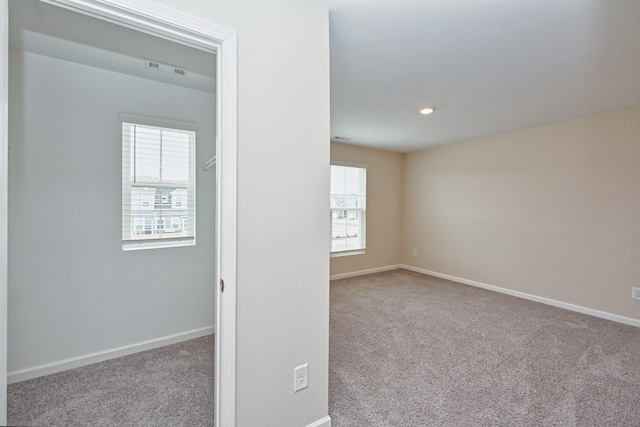 carpeted empty room featuring recessed lighting, visible vents, and baseboards