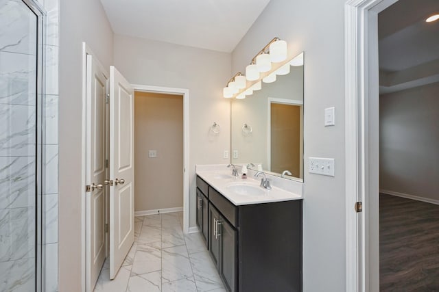 full bath with double vanity, marble finish floor, baseboards, and a sink