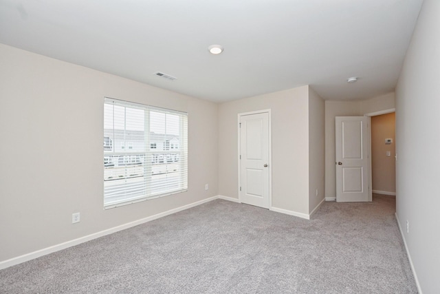 carpeted empty room with visible vents and baseboards