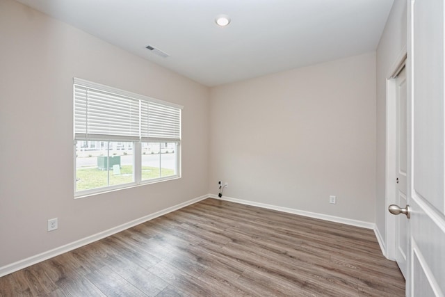 empty room with baseboards, visible vents, and wood finished floors