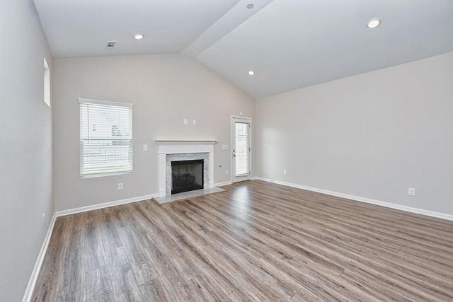 unfurnished living room featuring lofted ceiling, a fireplace, wood finished floors, and a wealth of natural light