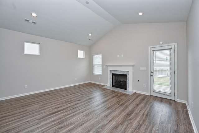 unfurnished living room with baseboards, visible vents, wood finished floors, vaulted ceiling, and a fireplace