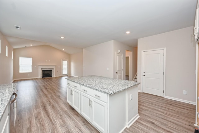 kitchen with lofted ceiling, light wood-style flooring, visible vents, white cabinets, and a center island