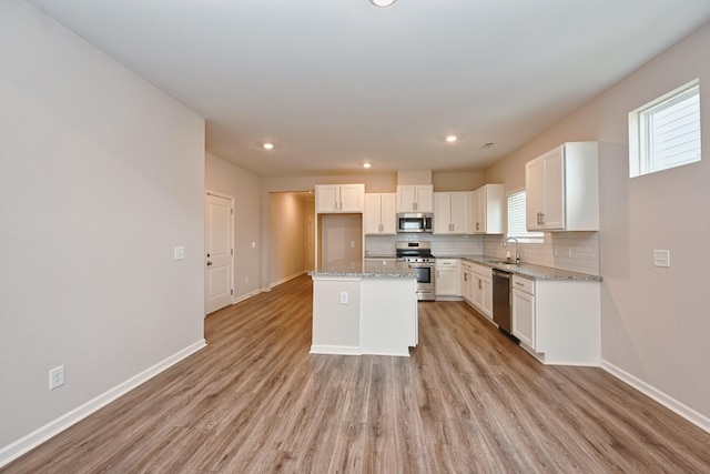 kitchen with baseboards, appliances with stainless steel finishes, decorative backsplash, and light wood-style flooring