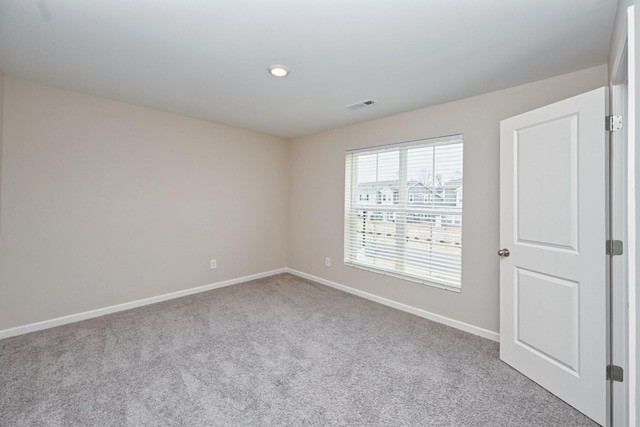 unfurnished room with carpet, visible vents, and baseboards