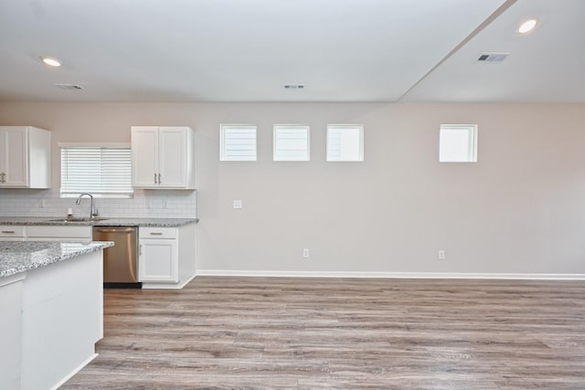 kitchen with light wood finished floors, decorative backsplash, white cabinetry, a sink, and dishwasher