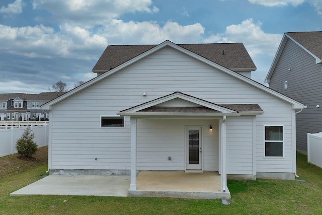 rear view of property featuring fence private yard, a patio area, a shingled roof, and a lawn