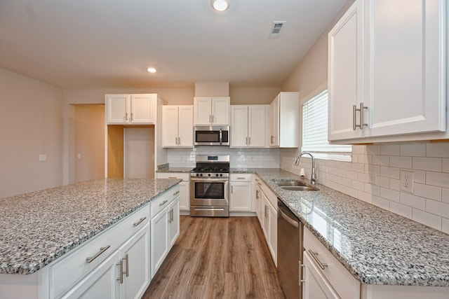 kitchen featuring stainless steel appliances, a sink, visible vents, white cabinets, and light wood-type flooring